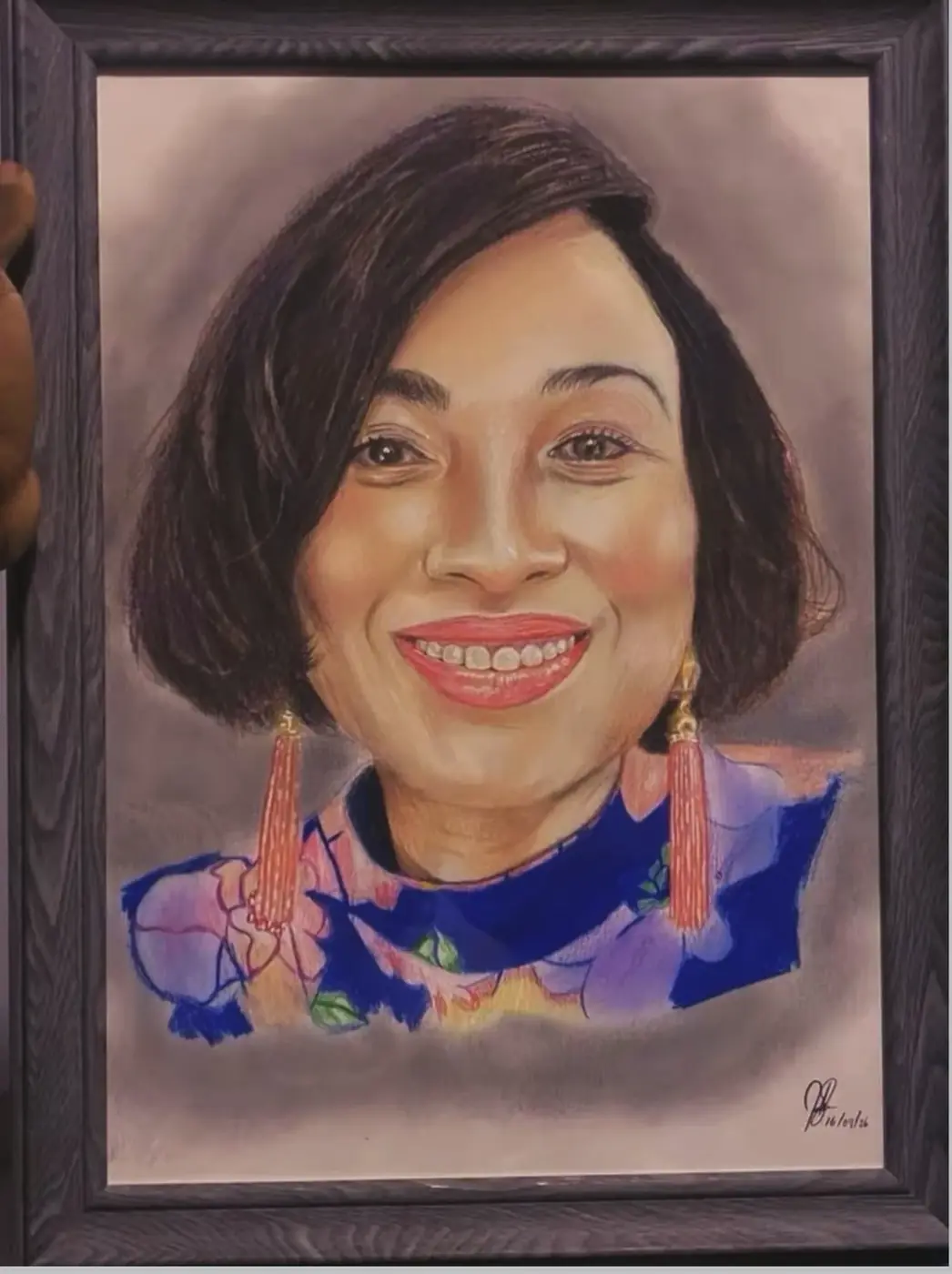 Framed coloured-pencil portrait of a smiling woman in a floral top.