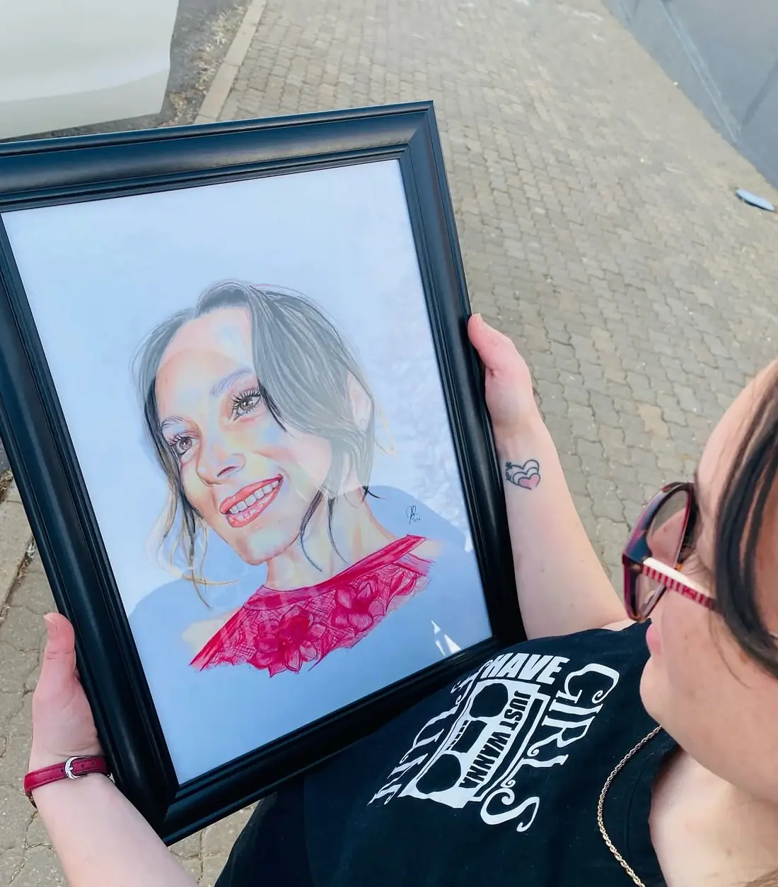 A person holding a framed portrait with a detailed red top.